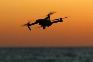 A quadrocopter with a photo camera flies over the sea.