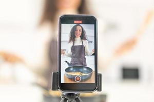 Latin woman shooting video and cooking at the kitchen photo