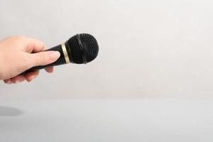 hand holding black microphone over grey background. copy space.media broadcast concept photo