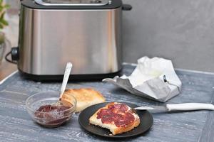 toasts with butter and berry jam on a wooden table next to toaster. breakfast time. photo