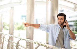 inessman pointing to something while using a smartphone to talk with his friend at the outdoor photo