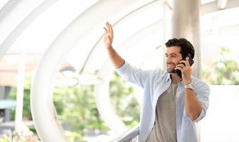 el hombre de negocios saluda y usa un teléfono inteligente para hablar con su amigo al aire libre. foto