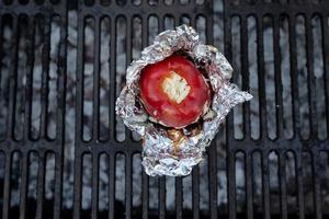 Top view shot of a red bell pepper filled with cheese on a grill outdoors photo