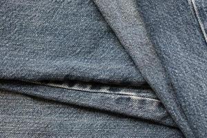 Detailed abstract texture of dark blue denim cloth. Background image of old used denim trousers fabric photo