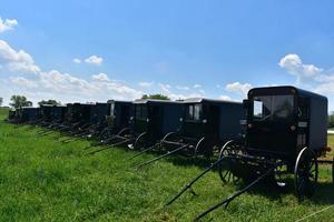 granja con un montón de buggies amish estacionados en un campo foto