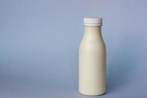 una botella de leche blanca, resaltada en un fondo azul, primer plano. foto
