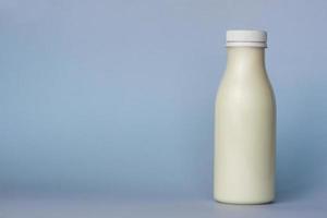 A bottle of white milk, highlighted on a blue background, close-up. photo