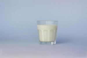 A glass of white milk, highlighted on a blue background, close-up. photo