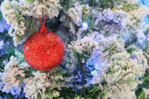 Christmas tree decorated with red ball on pine branches background photo