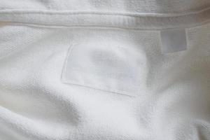 Blank white clothes label on new cotton shirt background photo
