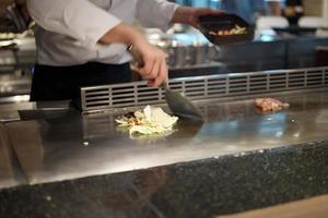 Japanese chef cooking meat in teppanyaki restaurant photo