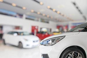 primer plano de la parte delantera del coche nuevo en el fondo de la sala de exposición foto