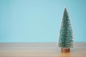 christmas tree on wood table with blue wall background photo