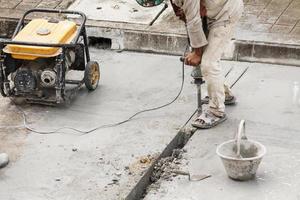 Construction worker using jackhammer drilling concrete surface photo