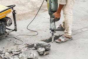 trabajador de la construcción con martillo perforador de superficie de hormigón foto