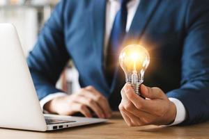 Innovation through ideas and inspiration ideas. Human hand holding light bulb to illuminate, idea of creativity and inspiration concept of sustainable business development. photo
