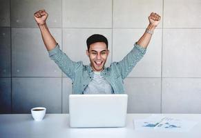 Small Business and Successful Concept. Young Asian Businessman Glad to recieve a Good News or High Profits from Computer Laptop, Own Business Achieves Goals. Raising Arms to Celebrating Success photo