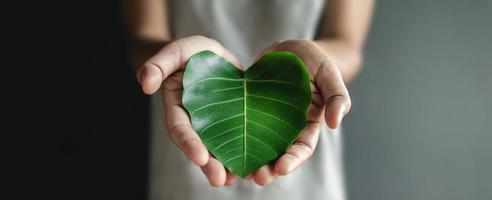 Green Energy, ESG, Renewable and Sustainable Resources. Environmental and Ecology Care Concept. Close up of Hand holding a Heart Shape Green Leaf photo