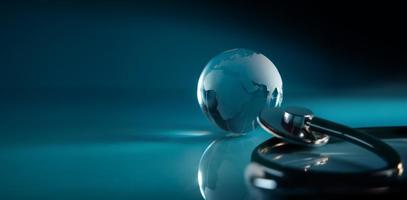 World Health Day. Global Health Care Concept. Transparent Glass Globe and Stethoscope lay on Blue background. Modern and Digital Technology Color Tone. Wide and Long size photo