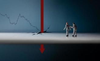 Recession, Inflation and Depression Concepts. Economic Crisis. Graph Fall Down, Business Collapse. Two Miniature Figure of Businessman Looking at a Red Graph Arrow Falling Deep Down photo