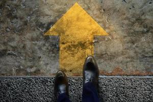 Start and Challenge Concept. a Business Man on Formal Shoes Steps to Follow a Yellow Arrow, Get Ready to Moving Forward or take a Chance to Success. Top View photo