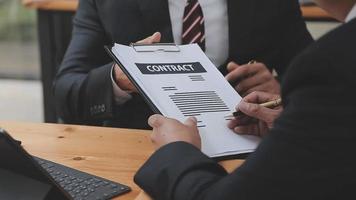 Business and lawyers discussing contract papers with brass scale on desk in office. Law, legal services, advice, justice and law concept picture with film grain effect video