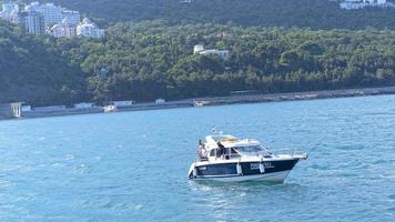 Yalta, Crimea-June 11, 2021 Seascape with a view of a boat with fishermen on the background of the shore photo