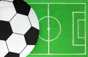 plantilla de mesa de fiesta de fútbol. plato grande vacío pintado como una pelota de fútbol. El tapete para platos tiene un dibujo como un campo de fútbol hecho de fieltro verde. vista superior, lugar para sus productos y texto. foto