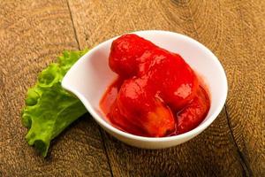 tomates pelados en un bol sobre fondo de madera foto