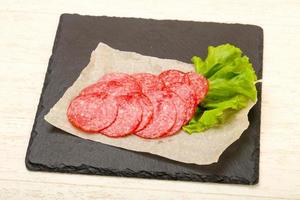 Salami sausage on wooden board and wooden background photo