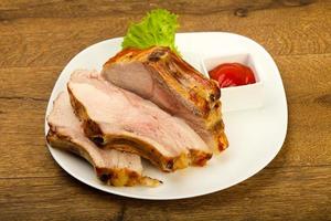Roasted pork on the plate and wooden background photo