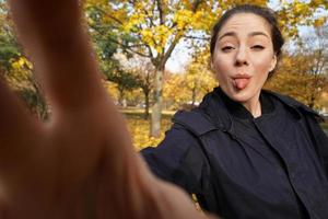 sassy young woman in her 20s sticking out her tongue taking selfie photo