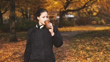 mujer joven bebiendo café para llevar mientras está en movimiento foto