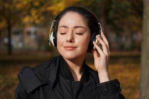 mujer joven escuchando música con auriculares inalámbricos al aire libre foto