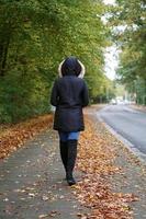 unrecognizable woman wearing winter coat and boots walking down the street photo