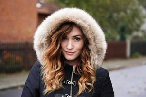 young woman wearing winter coat with fake fur hood outdoors photo