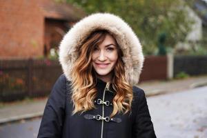smiling young woman wearing winter coat with fake fur hood photo