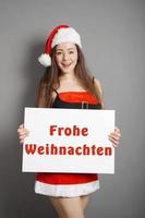 Frohe Weihnachten - female santa wishes merry christmas in German photo
