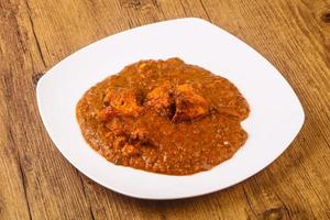 Masala chicken on the plate and wooden background photo