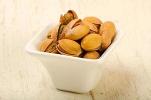 Pistachio in a bowl on wooden background photo