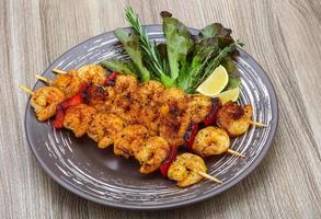 Prawn skewer on the plate and wooden background photo