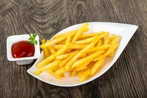 French fries in a bowl on wooden background photo