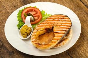 Grilled salmon on the plate and wooden background photo