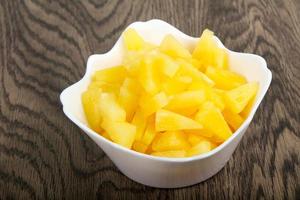 Canned pineapple in a bowl on wooden background photo