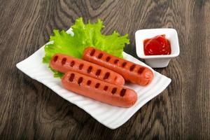 Grilled sausages on the plate and wooden background photo