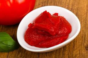 Tomato paste in a bowl on wooden background photo