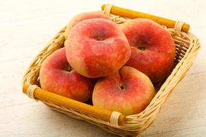 Sweet peaches in a basket on wooden background photo