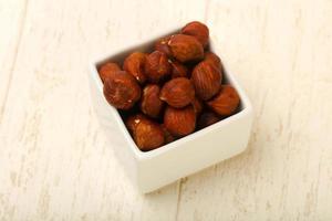 Hazelnut heap in a bowl on wooden background photo