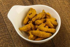 Tumeric roots in a bowl on wooden background photo