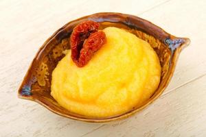 Polenta in a bowl on wooden background photo